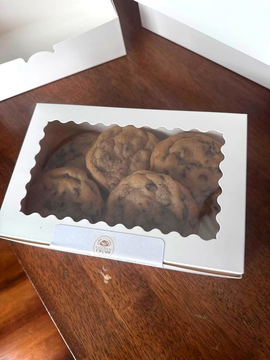 A Golden Crumb branded cookie box filled with chocolate chip cookies