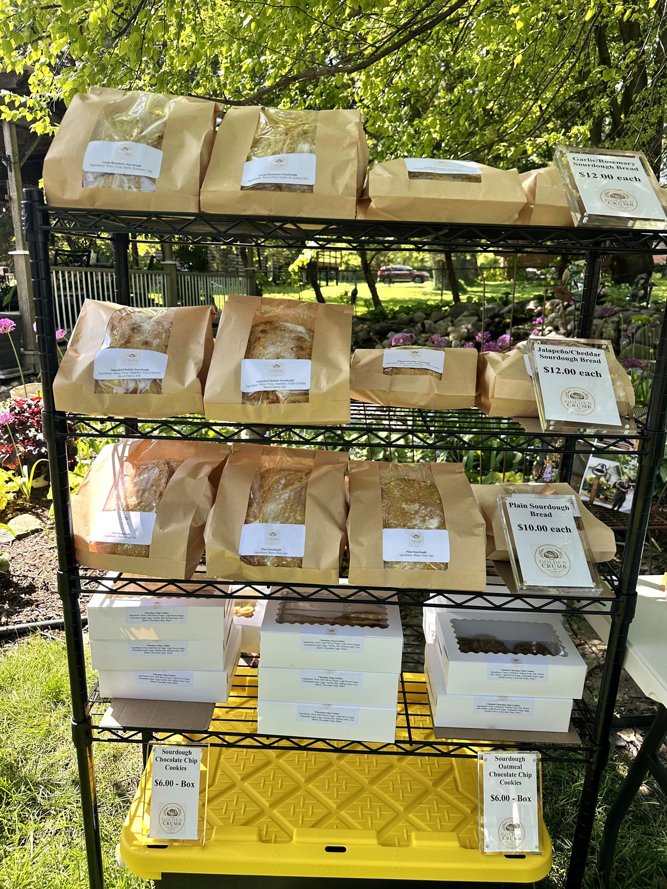 Full display rack with sourdough loaves, cookies, and price signs