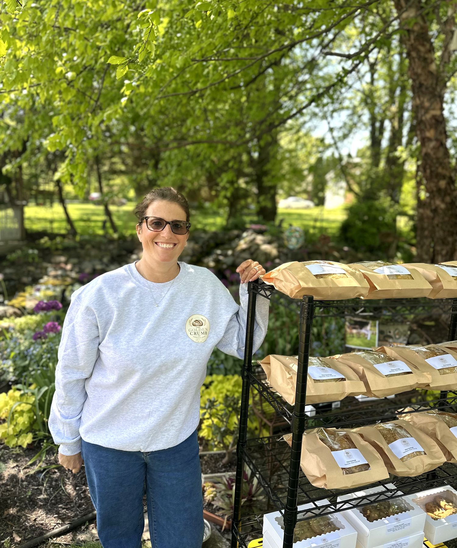 Michelle smiling at The Golden Crumb booth, full bread display behind her